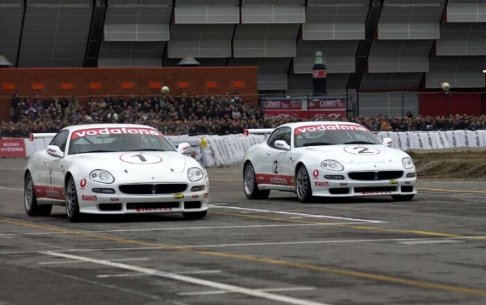 Luciano Burti and Andrea Bertolini demonstrate the Maserati Trofeo sportscar around the Bologna Motor show's circuit