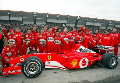 the Formula 1 World Championship winning Ferrari team pose with the victorious F2002 in Bologna