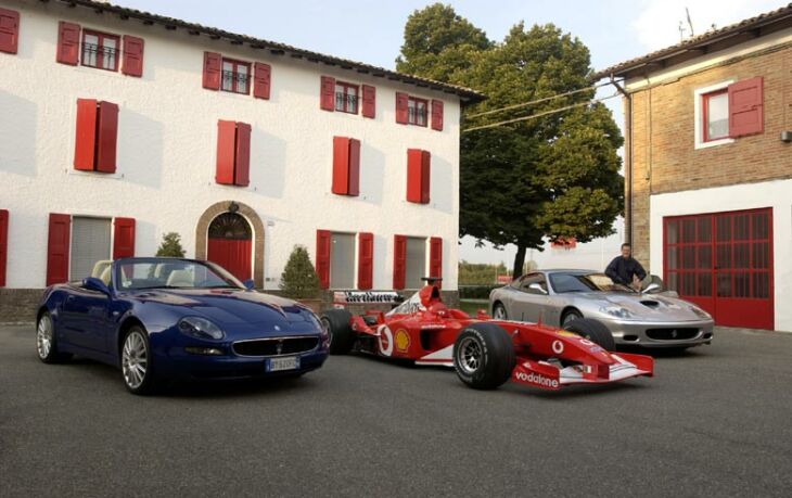 Michael Schumacher poses with his Formula 1 World Championship winning Ferrari F2002 and his road cars, a new Ferrari 575M and Maserati Spyder