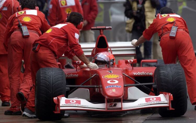 Michael Schumacher's Ferrari is pushed into the garage during a wet free practice session